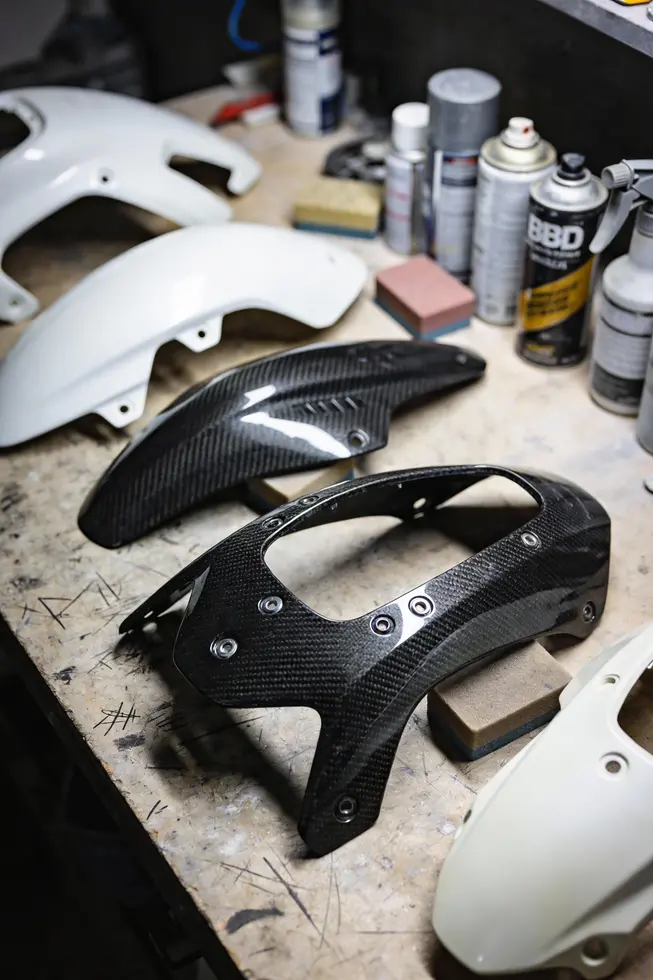 Tech preps off-bike fairings with proper surface filling and temperature control for an even coating.
